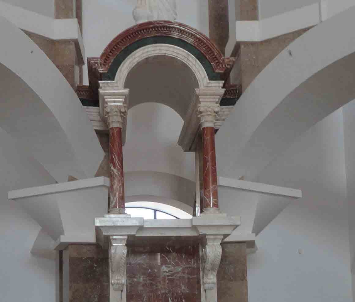 Interior de un edificio con arcos y columnas decorativas.
